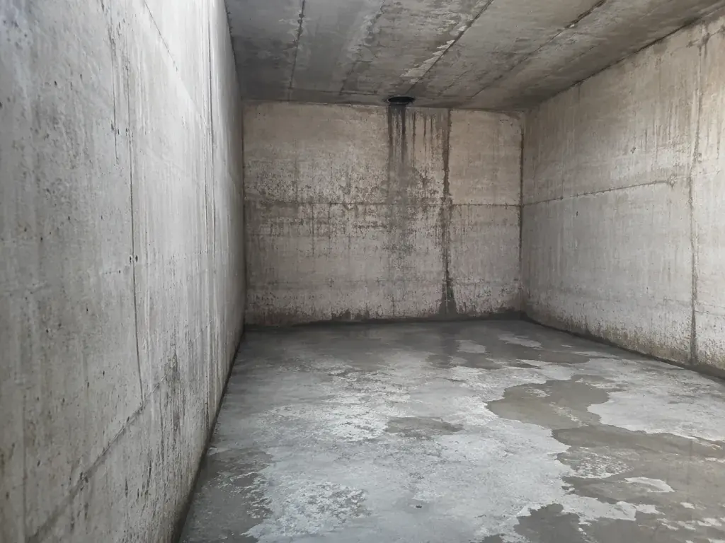 Empty concrete cistern with stained, porous walls, ready for a liner